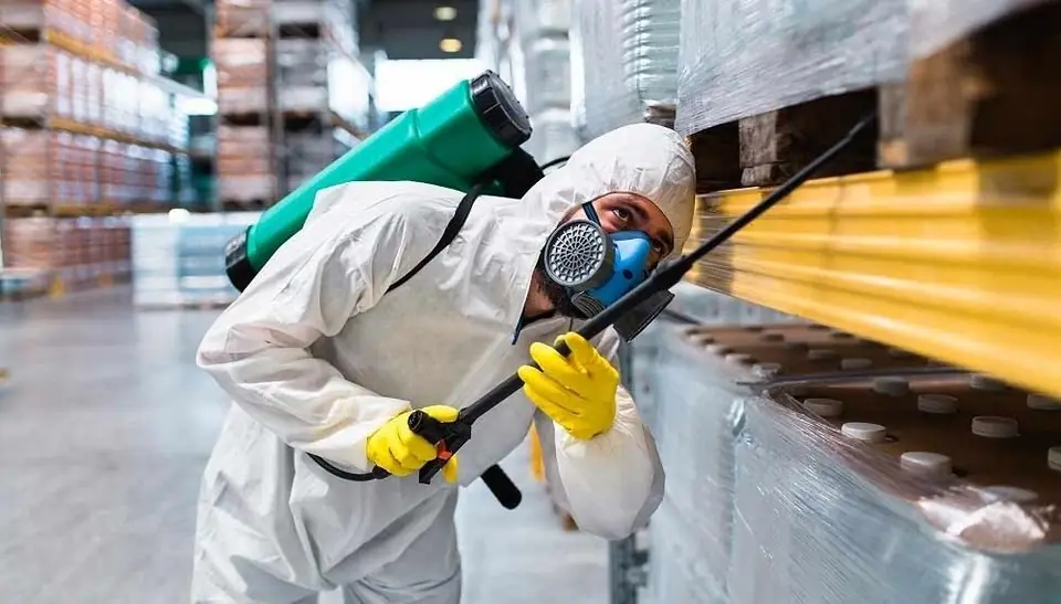 Técnico de desinsectación aplicando un tratamiento en un almacén